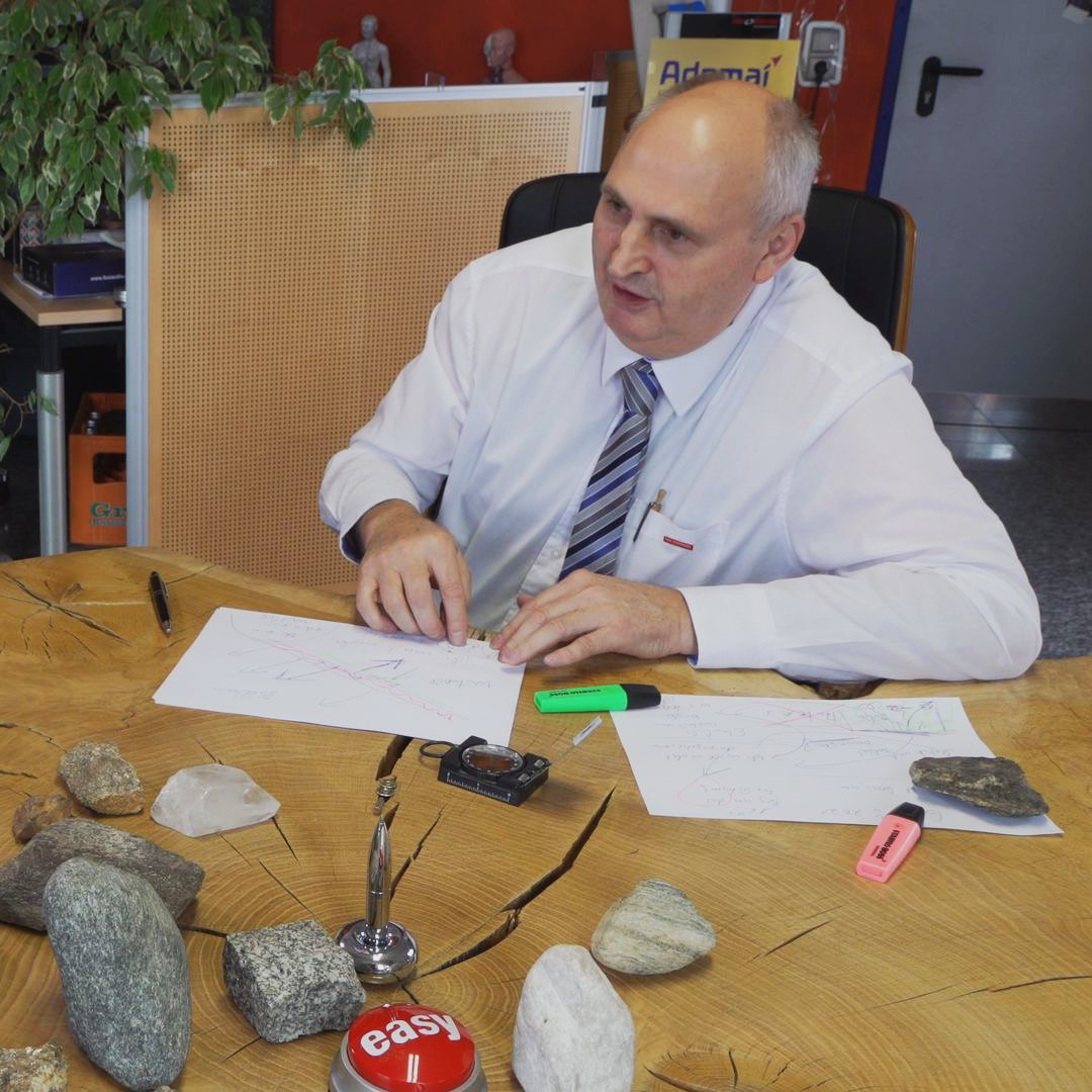 Mann im weißen Hemd am Tisch mit Steinen, Notizen und „Easy“-Button.